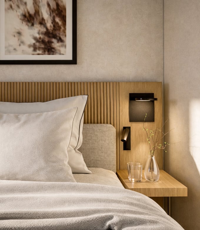 A bed with light bedding abuts a fluted wooden headboard. A floating nightstand holds a glass and a vase with twigs, illuminated by wall lamps, in a modern bedroom.