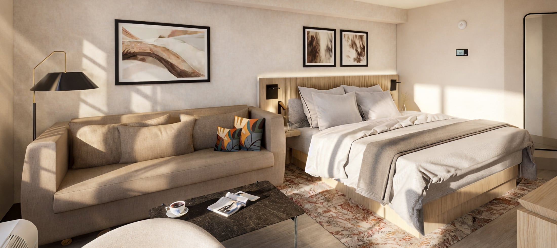 A modern hotel room features a king bed, bedside tables, and a beige sofa with colorful cushions. Sunlight illuminates the room's warm, minimalist decor.