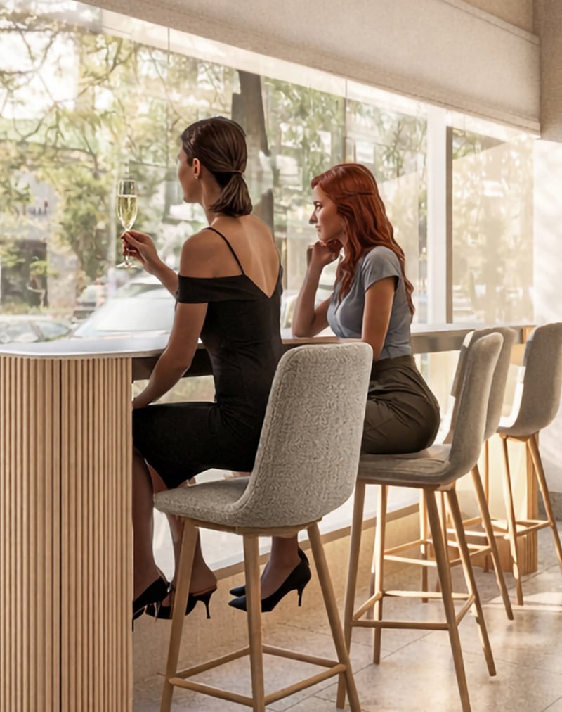 Two women sit at a bar counter by large windows. One in a black dress holds a champagne flute, looking outside; the other with red hair watches her, chin resting on hand.