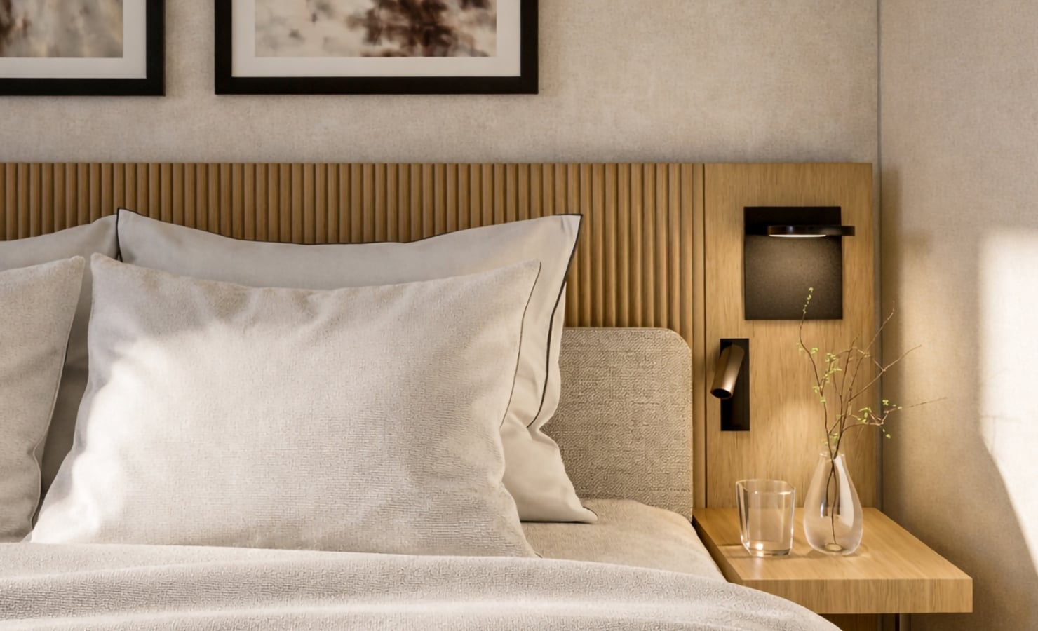 A bed with light pillows and duvet, a slatted wooden headboard with artwork above, and a bedside table holding a glass, vase, and contemporary lamps in a bright room.