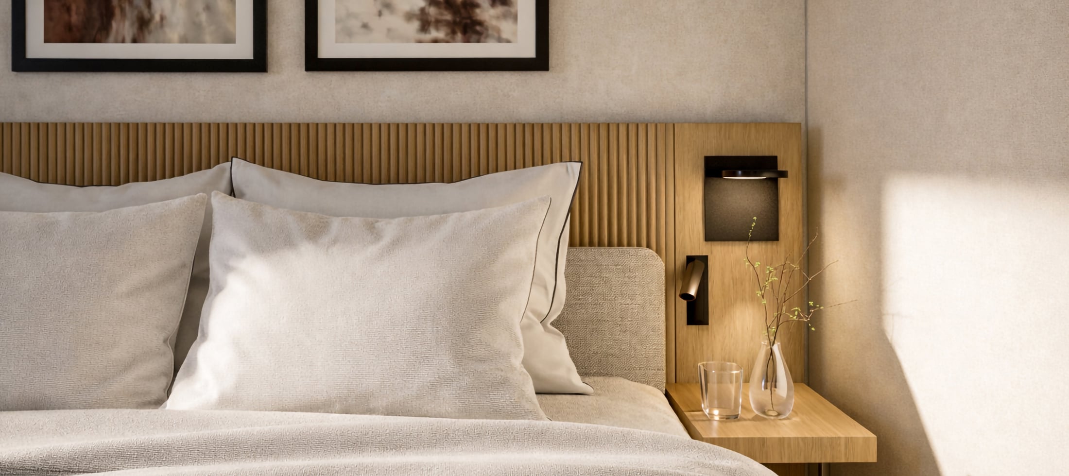 A bed with light pillows and duvet, a slatted wooden headboard with artwork above, and a bedside table holding a glass, vase, and contemporary lamps in a bright room.