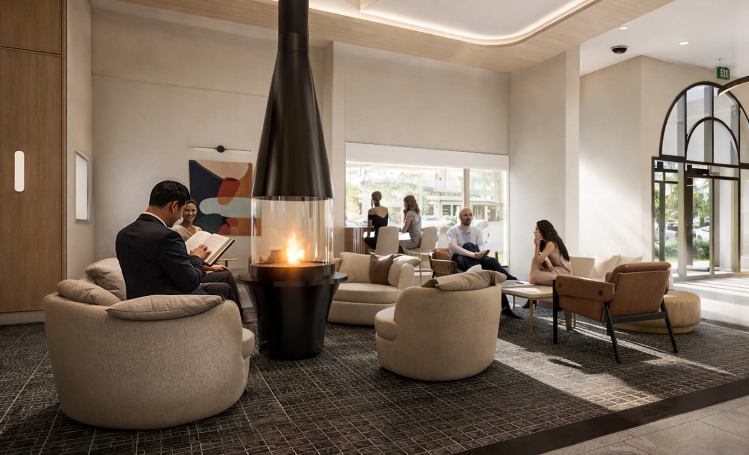 People are reading, conversing, and relaxing in a modern lounge featuring a central glass fireplace, comfortable seating, and large windows overlooking outdoors. An "EXIT" sign is visible.