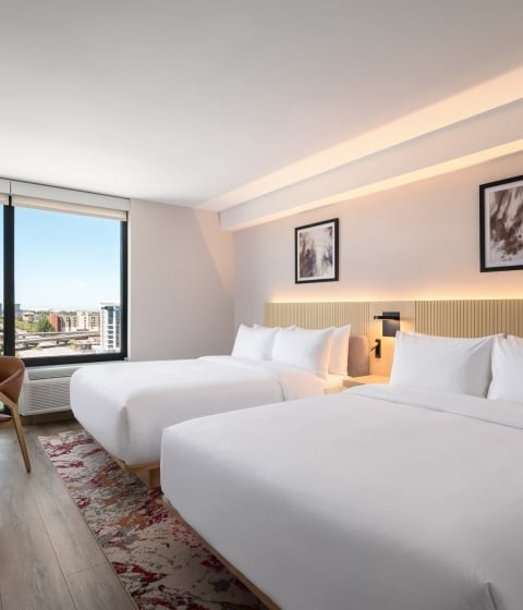 Two queen beds with a city view out the window