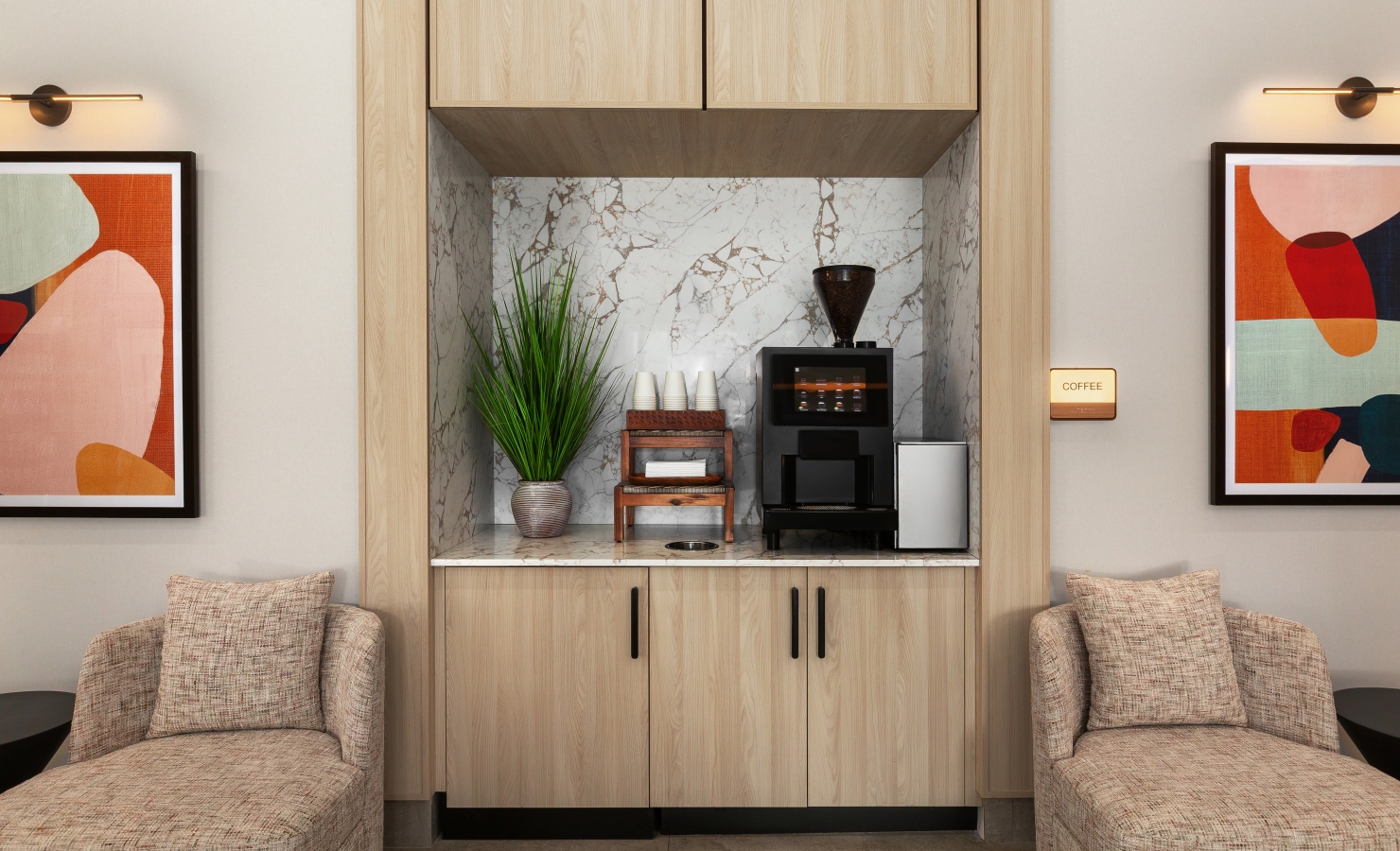 Built-in coffee bar with marble backsplash, coffee machine, grinder, cups, and a potted plant framed by wood cabinets.