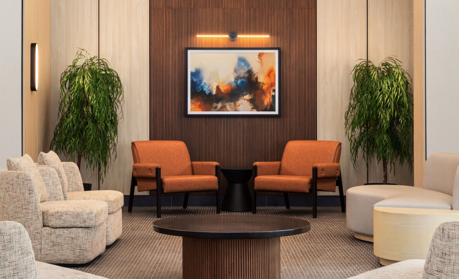 Modern hotel-style lounge with a wood-paneled accent wall, abstract framed painting, orange chairs, and green potted plants.